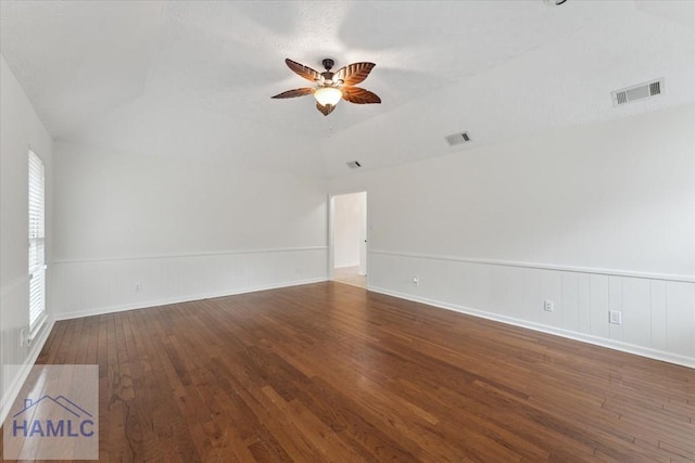 spare room featuring ceiling fan, hardwood / wood-style flooring, visible vents, and a wainscoted wall