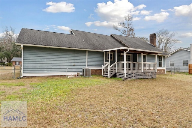 rear view of house with roof with shingles, a yard, a chimney, central AC unit, and fence