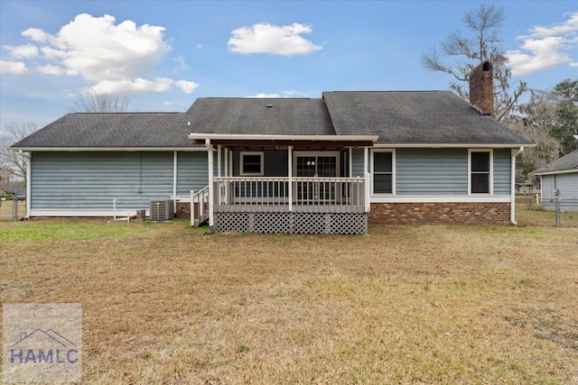 rear view of house with central air condition unit, brick siding, fence, a yard, and a chimney