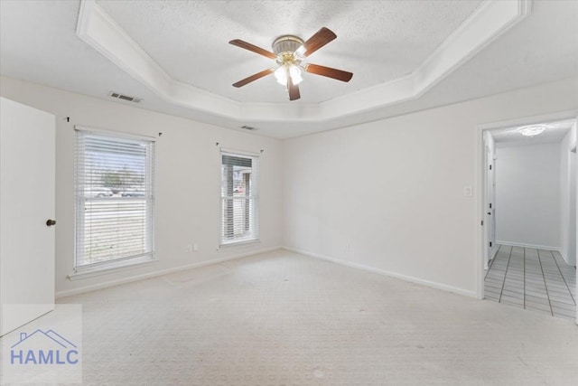 spare room with a wealth of natural light, a raised ceiling, visible vents, and carpet flooring