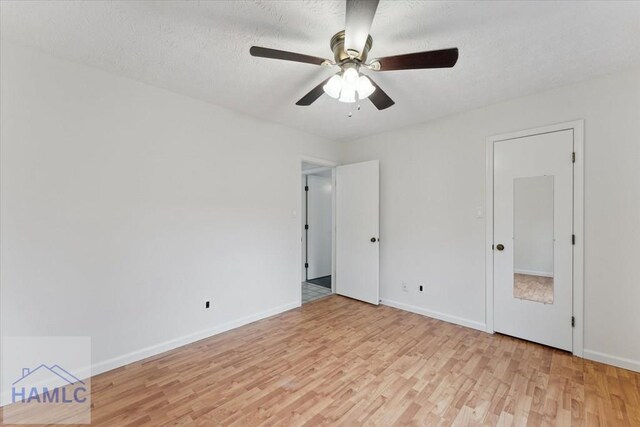 unfurnished bedroom with light wood-style floors, ceiling fan, baseboards, and a textured ceiling