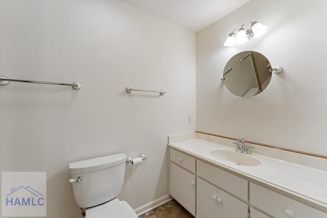 bathroom with toilet, baseboards, and vanity