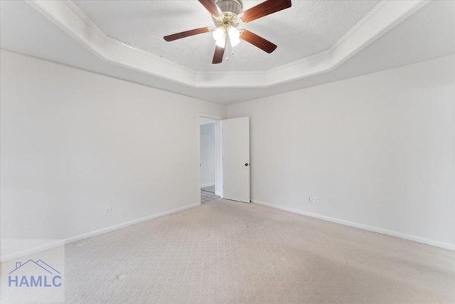 unfurnished room featuring a ceiling fan, carpet, a raised ceiling, and baseboards