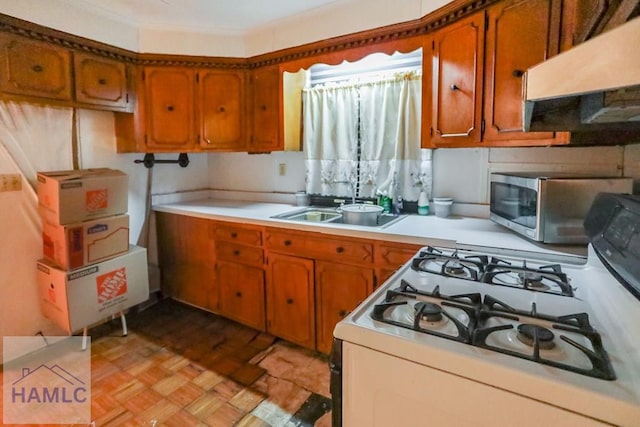707 Church St, Claxton, GA 30417 - kitchen with under cabinet range hood, gas range gas stove, light countertops, and brown cabinetry