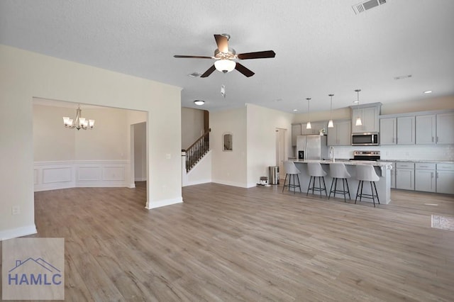 702 Fairview Cir, Hinesville, GA 31313 - living area with light wood-style floors, a ceiling fan, stairway, a chandelier, and a wainscoted wall