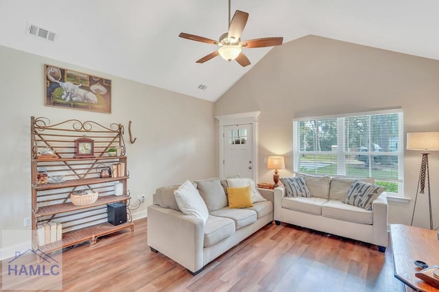 living room with hardwood / wood-style flooring, ceiling fan, and high vaulted ceiling