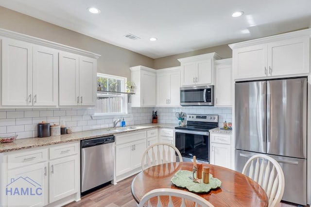 kitchen with white cabinets, light stone counters, sink, and appliances with stainless steel finishes