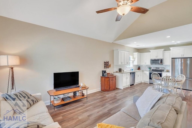 living room with ceiling fan, light hardwood / wood-style flooring, and high vaulted ceiling