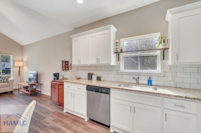 kitchen featuring lofted ceiling, white cabinets, sink, stainless steel dishwasher, and light wood-type flooring