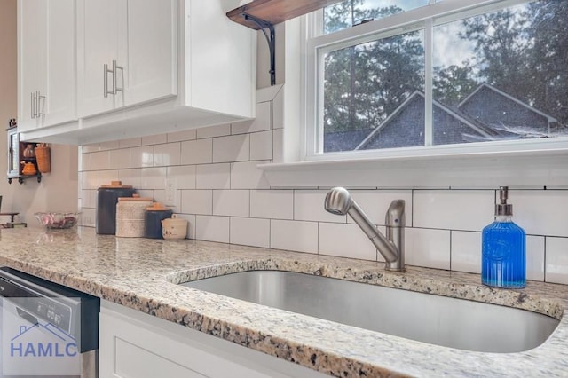 kitchen featuring white cabinetry, decorative backsplash, dishwasher, and sink