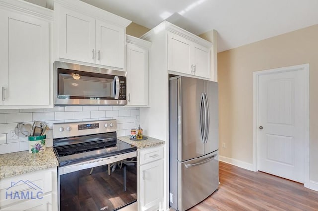 kitchen with light wood-type flooring, white cabinetry, backsplash, and appliances with stainless steel finishes