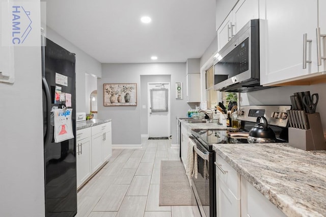 kitchen featuring white cabinetry, sink, stainless steel appliances, and light stone counters