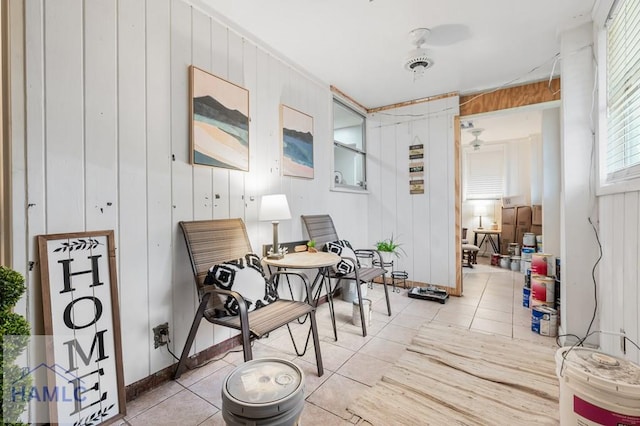 sitting room featuring light tile patterned floors and wooden walls