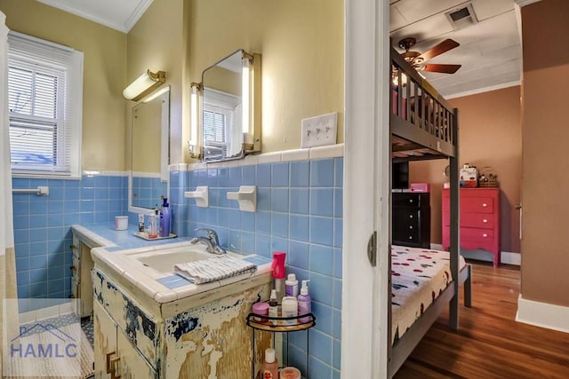 bathroom with visible vents, a ceiling fan, wood finished floors, tile walls, and crown molding