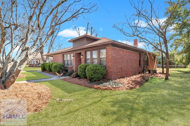 view of home's exterior with a yard, brick siding, and a chimney