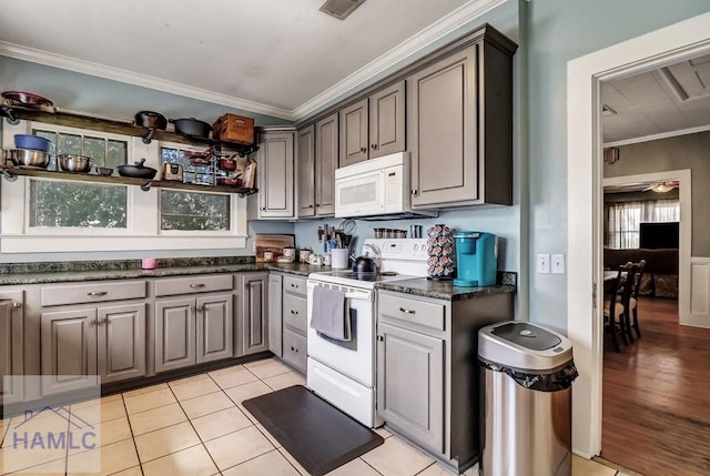 kitchen with dark countertops, visible vents, ornamental molding, light tile patterned flooring, and white appliances