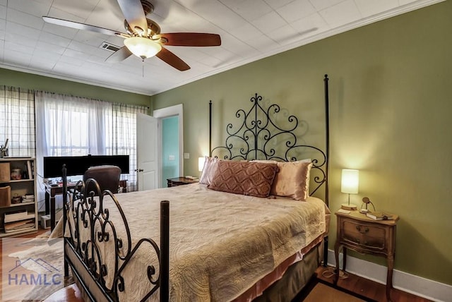 bedroom with visible vents, ceiling fan, baseboards, ornamental molding, and wood finished floors