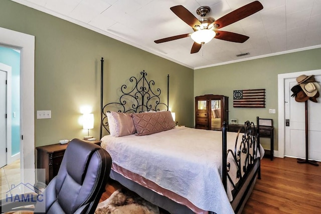 bedroom featuring wood finished floors, baseboards, visible vents, ceiling fan, and ornamental molding