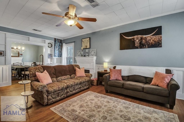 living area featuring visible vents, wood finished floors, a fireplace, and ornamental molding