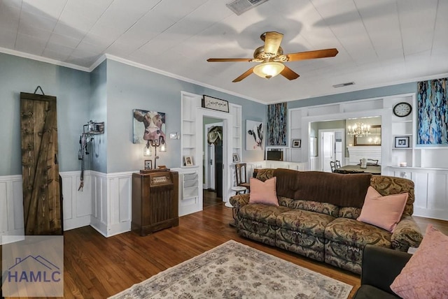 living area with built in features, dark wood-style flooring, visible vents, and a wainscoted wall