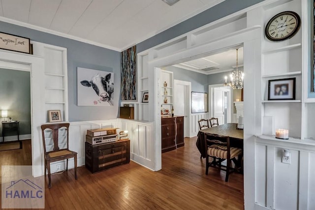 interior space featuring hardwood / wood-style floors, crown molding, built in features, and an inviting chandelier