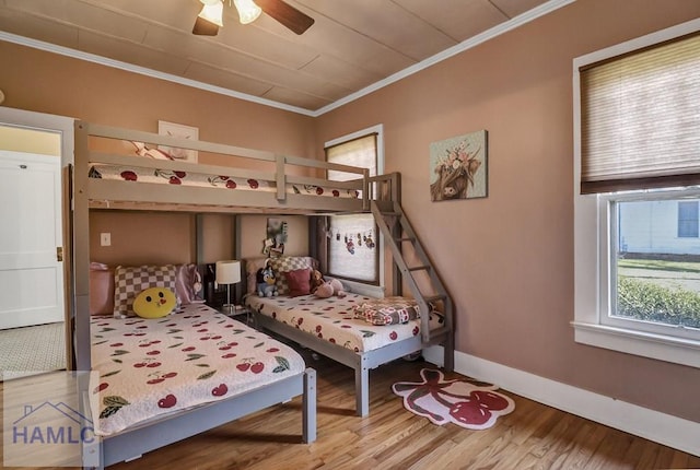 bedroom featuring ceiling fan, baseboards, wood finished floors, and crown molding