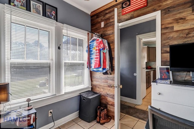 interior space with light tile patterned floors, baseboards, wood walls, and ornamental molding