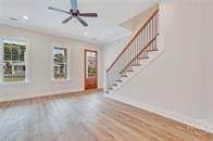 49 Salt Marsh Dr, Midway, GA 31320 - unfurnished living room with stairway, wood finished floors, plenty of natural light, and ceiling fan