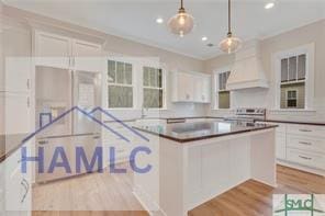 49 Salt Marsh Dr, Midway, GA 31320 - kitchen with light wood-type flooring, white cabinetry, a center island, hanging light fixtures, and custom range hood