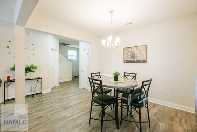 dining area with light wood-type flooring and an inviting chandelier