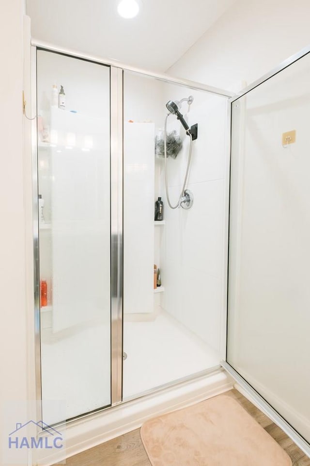 bathroom with hardwood / wood-style floors and a shower with shower door