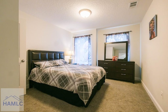 bedroom with a textured ceiling and light colored carpet