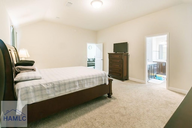 bedroom featuring connected bathroom, light colored carpet, and vaulted ceiling