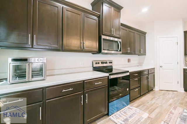 kitchen with dark brown cabinets, light hardwood / wood-style floors, and stainless steel appliances