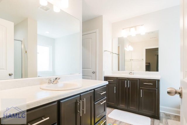 bathroom with wood-type flooring, vanity, and a shower with shower door