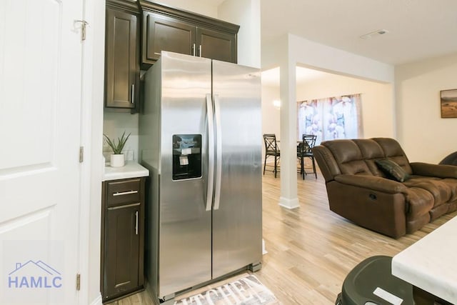 kitchen with stainless steel fridge, dark brown cabinetry, and light hardwood / wood-style floors