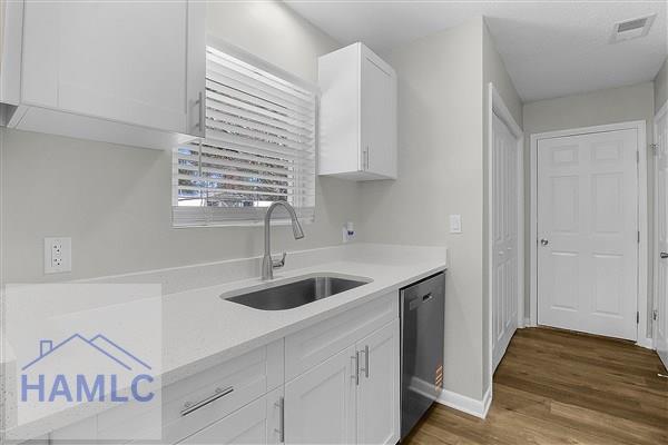 kitchen with sink, dark wood-type flooring, white cabinetry, and dishwasher