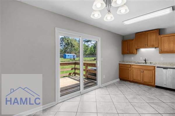 1110 Ricade Dr, Hinesville, GA 31313 - kitchen featuring brown cabinetry, a chandelier, stainless steel dishwasher, and light countertops