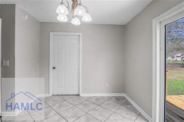 1110 Ricade Dr, Hinesville, GA 31313 - unfurnished dining area with light tile patterned floors, baseboards, an inviting chandelier, and a healthy amount of sunlight