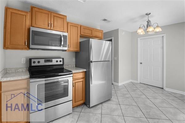 1110 Ricade Dr, Hinesville, GA 31313 - kitchen with stainless steel appliances, visible vents, light countertops, and an inviting chandelier