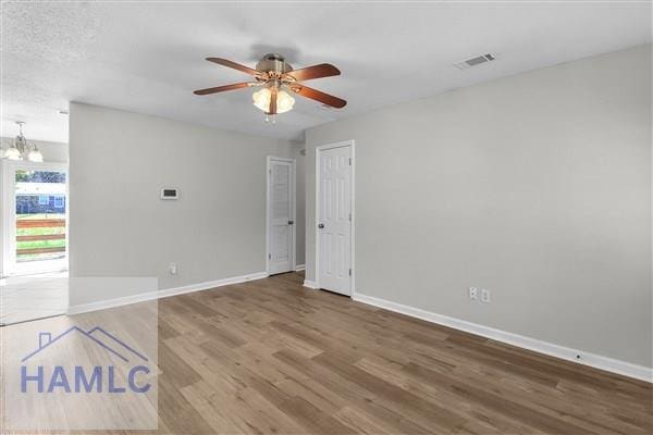 1110 Ricade Dr, Hinesville, GA 31313 - spare room featuring visible vents, baseboards, wood finished floors, and ceiling fan with notable chandelier