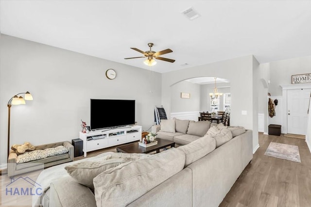 living room with light wood-type flooring and ceiling fan with notable chandelier