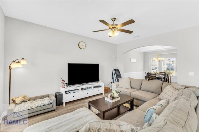 living room with ceiling fan with notable chandelier and wood-type flooring