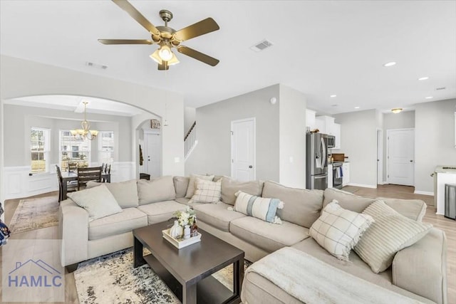 living room featuring light hardwood / wood-style floors and ceiling fan with notable chandelier