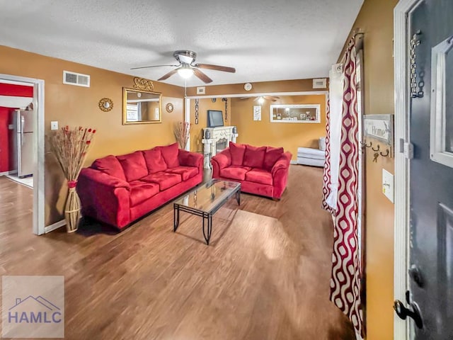 living room featuring a textured ceiling, ceiling fan, and wood-type flooring