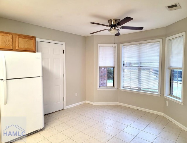 interior space with visible vents, brown cabinets, freestanding refrigerator, and baseboards