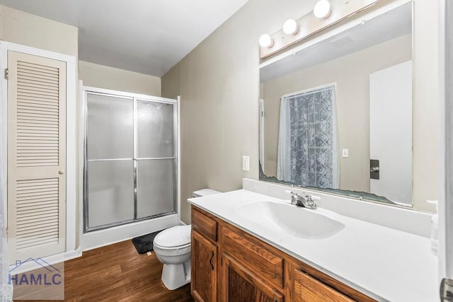 bathroom with vanity, a shower with door, toilet, and hardwood / wood-style floors