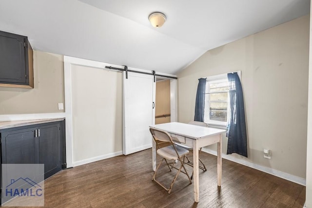 dining space with vaulted ceiling, dark hardwood / wood-style flooring, and a barn door