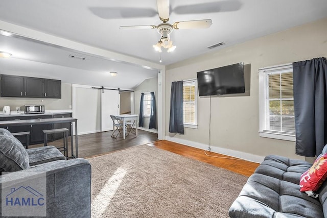 living room with vaulted ceiling, ceiling fan, a barn door, and dark hardwood / wood-style floors