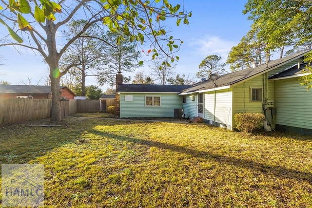 back of house with central air condition unit and a lawn